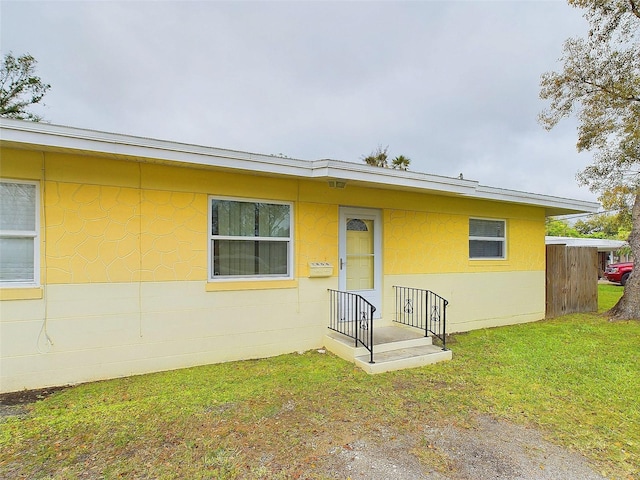 view of front facade featuring concrete block siding and a front lawn