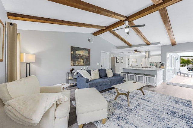 living room with light wood-style floors, visible vents, and vaulted ceiling with beams