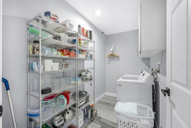 clothes washing area featuring cabinet space, wood finished floors, washer / dryer, and baseboards