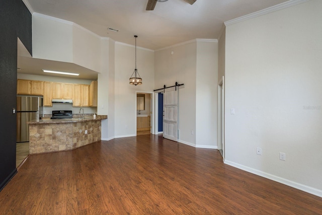 living area with ornamental molding, dark wood finished floors, ceiling fan, and a barn door