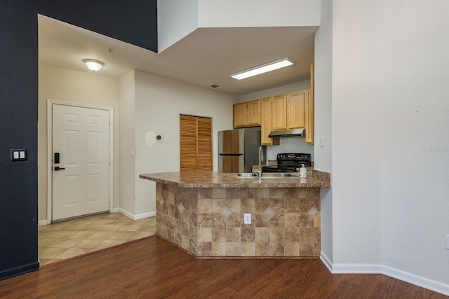 kitchen featuring black range with electric stovetop, wood finished floors, freestanding refrigerator, and under cabinet range hood