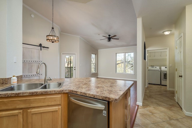 kitchen with a barn door, washing machine and clothes dryer, a peninsula, stainless steel dishwasher, and a sink