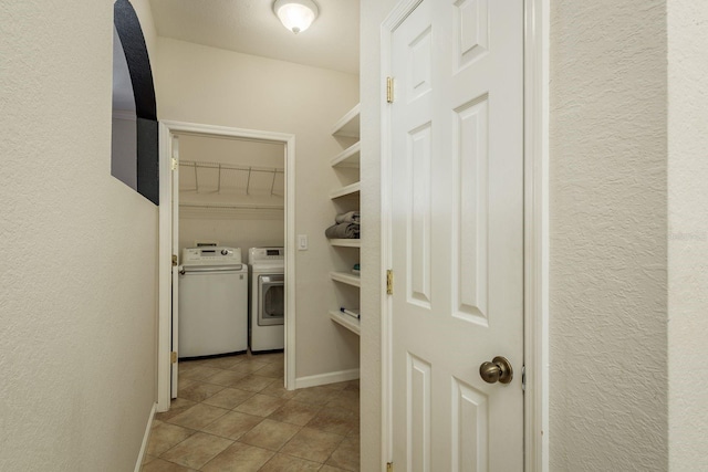 corridor with a textured wall, baseboards, separate washer and dryer, and tile patterned floors