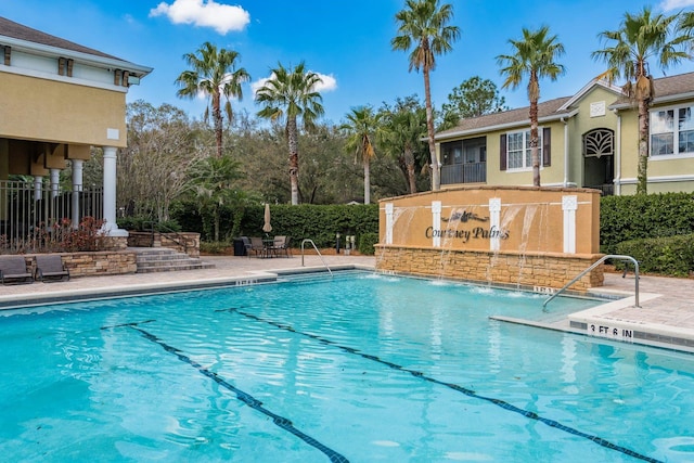 community pool with a patio area and fence