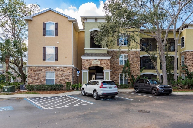 view of property with uncovered parking and cooling unit