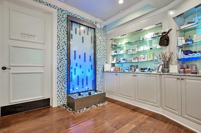 bar with ornamental molding and wood finished floors