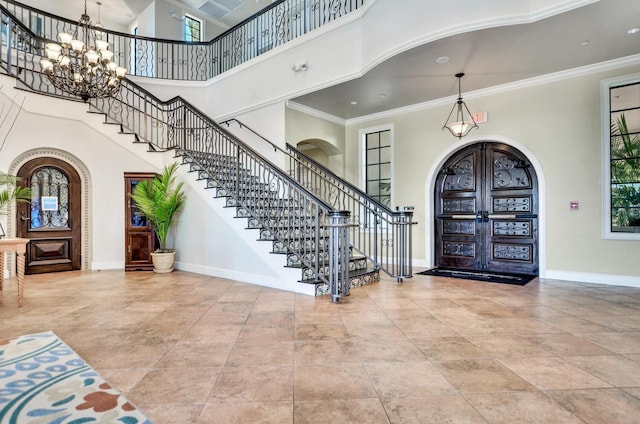 tiled foyer entrance with ornamental molding, arched walkways, a notable chandelier, and baseboards