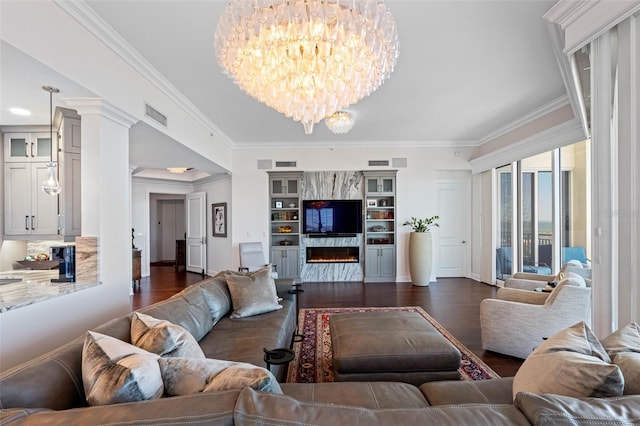 living area with dark wood-type flooring, a high end fireplace, visible vents, and an inviting chandelier