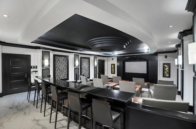 home theater featuring a barn door, ornamental molding, marble finish floor, a tray ceiling, and recessed lighting