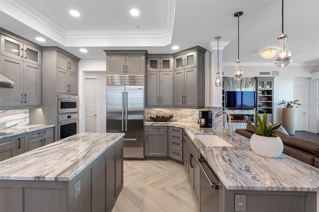 kitchen featuring stainless steel appliances, a peninsula, a sink, gray cabinets, and a raised ceiling