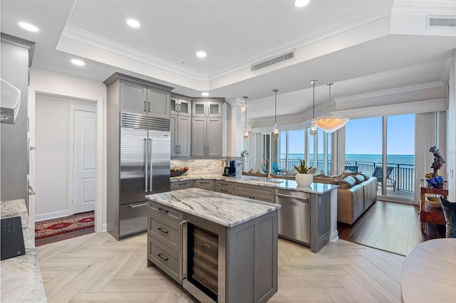 kitchen with crown molding, a raised ceiling, visible vents, gray cabinetry, and appliances with stainless steel finishes