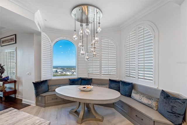 dining space with breakfast area, an inviting chandelier, ornamental molding, wood finished floors, and baseboards