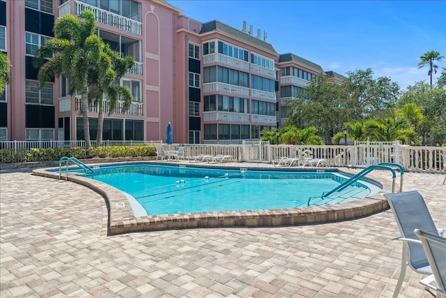 community pool with a patio area and fence