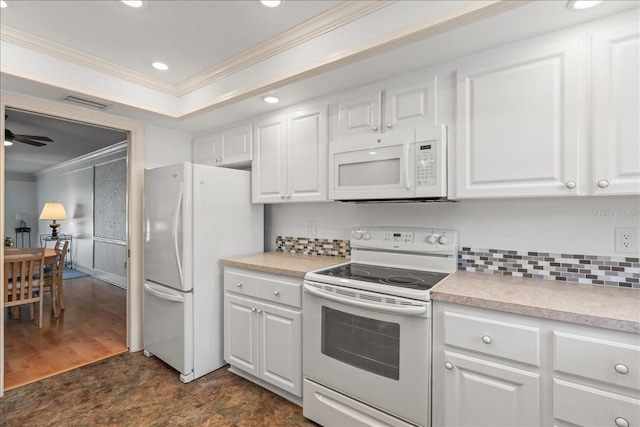 kitchen with a tray ceiling, crown molding, light countertops, white cabinets, and white appliances