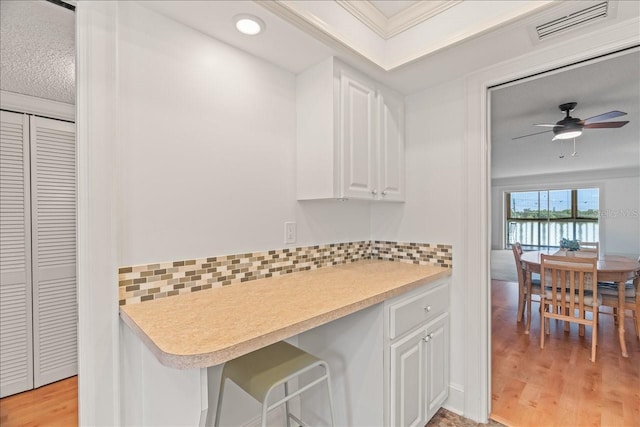 kitchen featuring light countertops, decorative backsplash, light wood-style flooring, and white cabinets