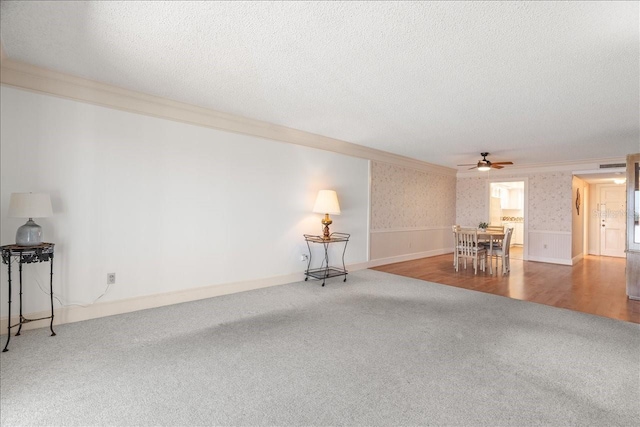 unfurnished living room with carpet floors, wallpapered walls, crown molding, and a textured ceiling