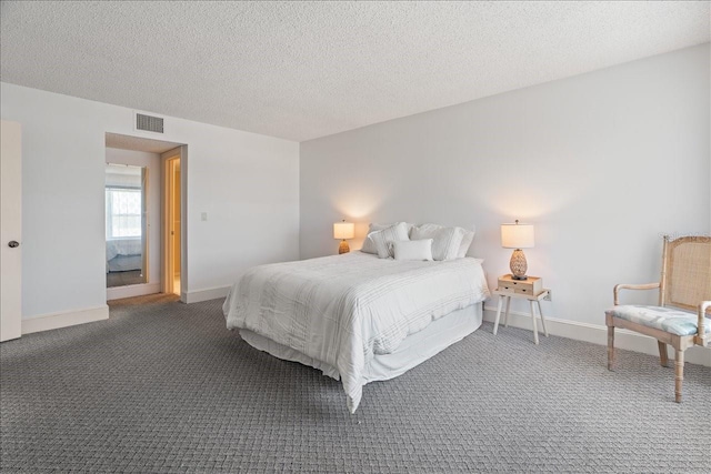 bedroom with a textured ceiling, dark carpet, and visible vents