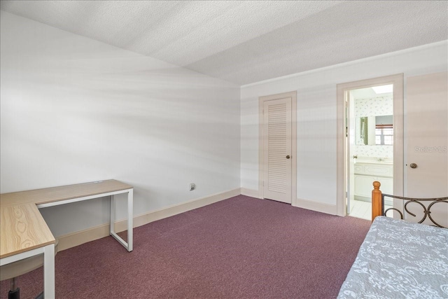 carpeted bedroom with ensuite bath, a textured ceiling, and baseboards