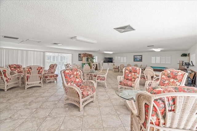 living area featuring visible vents, a textured ceiling, and light tile patterned flooring