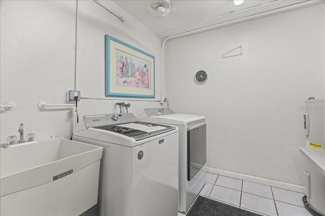 laundry area featuring light tile patterned flooring, a sink, laundry area, independent washer and dryer, and baseboards