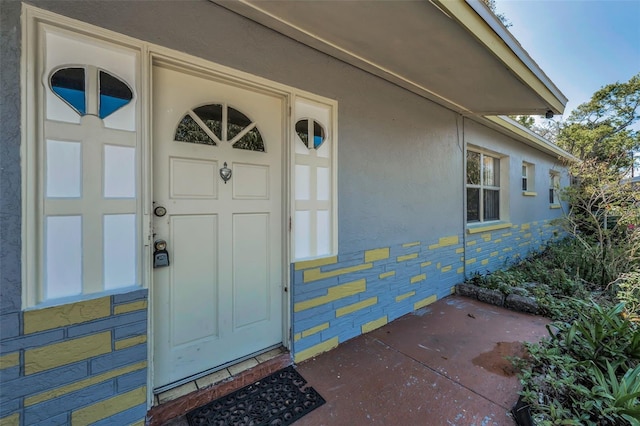 doorway to property with stucco siding and stone siding