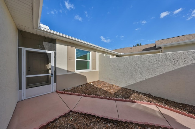 doorway to property with fence and stucco siding