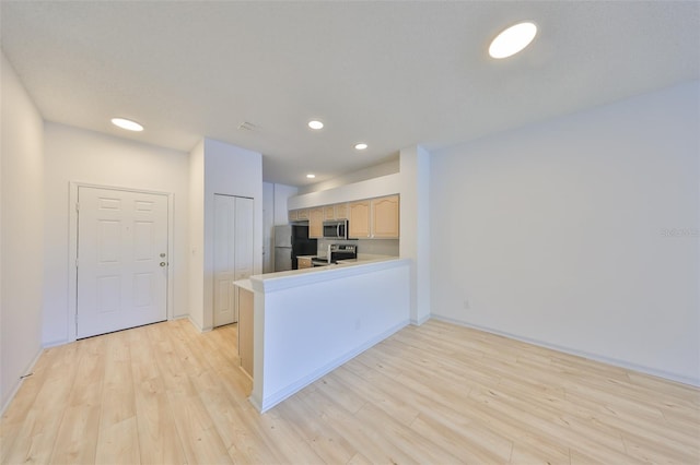 kitchen with a peninsula, light wood-style flooring, stainless steel appliances, and recessed lighting