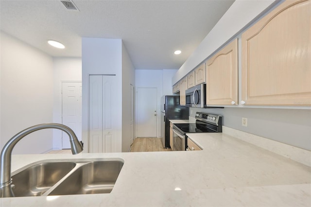 kitchen featuring light countertops, visible vents, light brown cabinetry, appliances with stainless steel finishes, and a sink