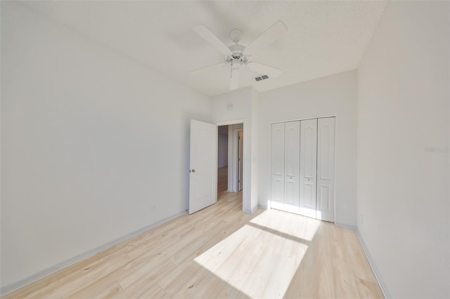 unfurnished bedroom featuring baseboards, visible vents, a ceiling fan, light wood-type flooring, and a closet