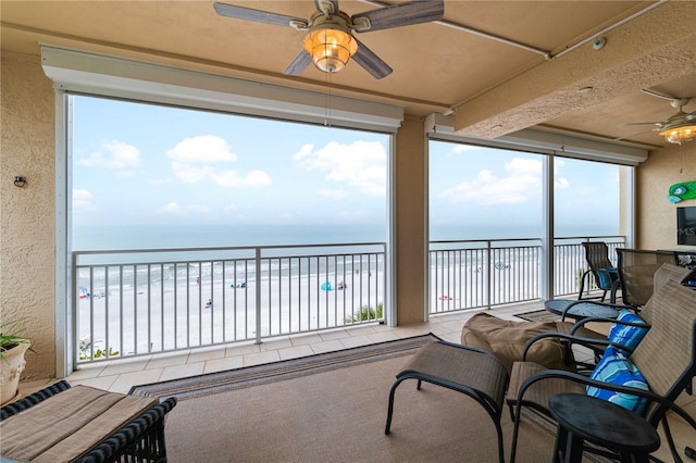 sunroom / solarium featuring a water view and ceiling fan