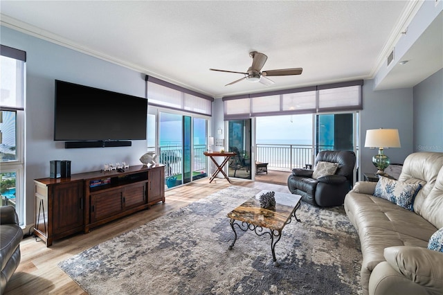 living room featuring visible vents, crown molding, ceiling fan, a wealth of natural light, and light wood-style floors