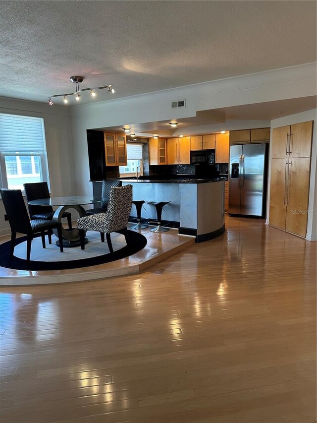 6425 Shoreline Dr Unit 10506, Saint Petersburg, FL 33708 - kitchen featuring stainless steel fridge with ice dispenser, black microwave, dark countertops, plenty of natural light, and a textured ceiling