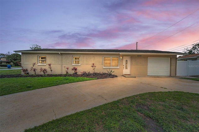 ranch-style house with a front yard, concrete driveway, brick siding, and an attached garage