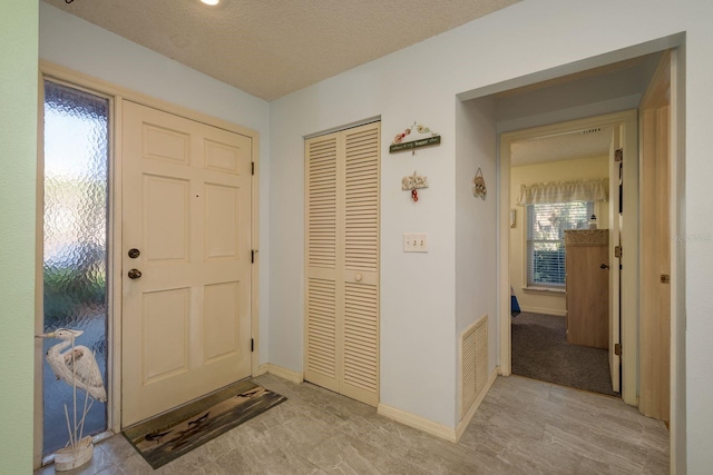 entryway featuring visible vents, a textured ceiling, and baseboards