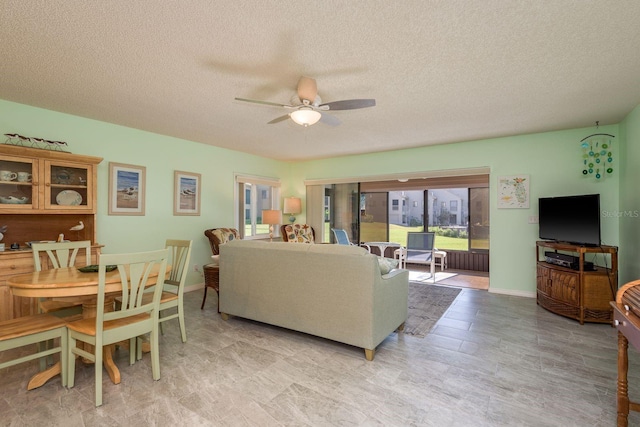 living area with ceiling fan, baseboards, and a textured ceiling