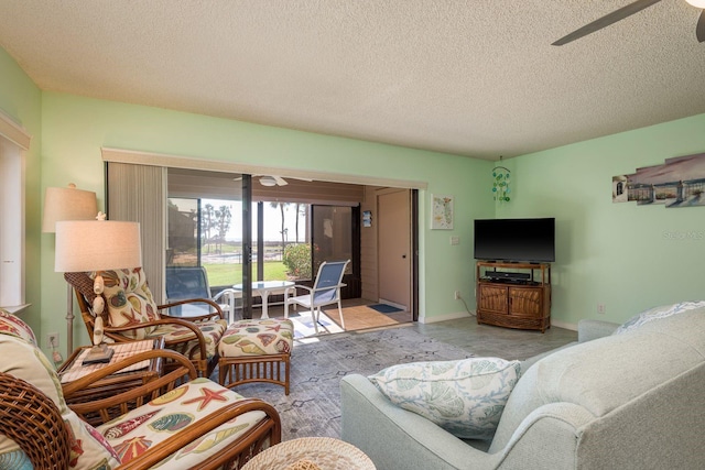 living area featuring ceiling fan, a textured ceiling, and baseboards