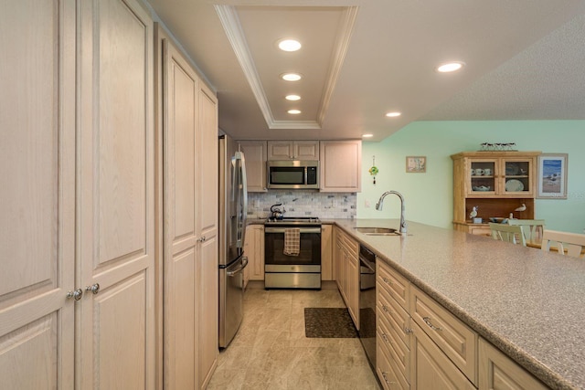 kitchen featuring a tray ceiling, stainless steel appliances, recessed lighting, backsplash, and a sink