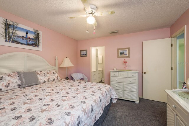 bedroom featuring visible vents, dark carpet, a ceiling fan, a textured ceiling, and ensuite bath