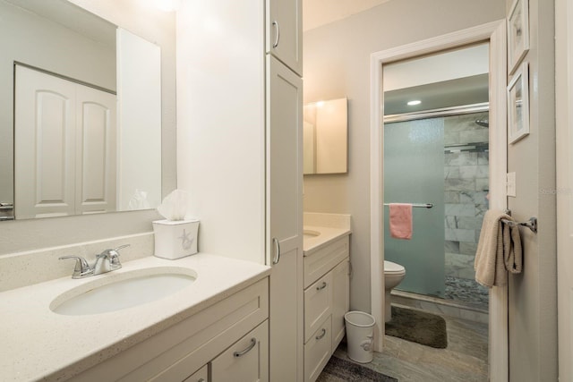 full bath with toilet, a shower stall, two vanities, and a sink