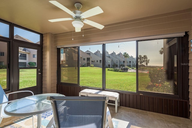 sunroom with a ceiling fan, a residential view, and a healthy amount of sunlight