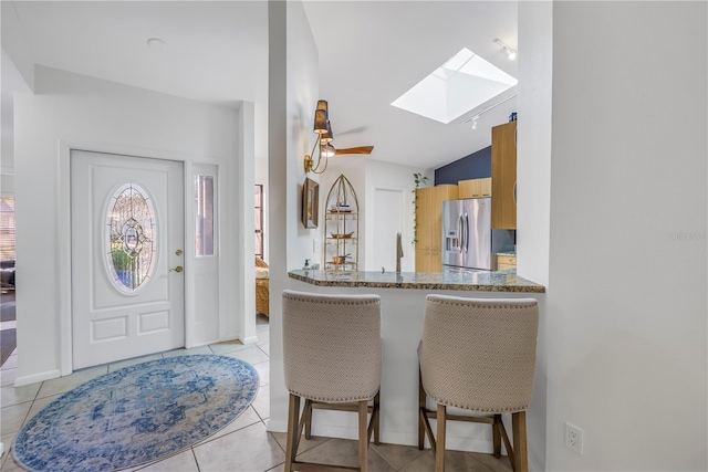entrance foyer with lofted ceiling with skylight and light tile patterned floors