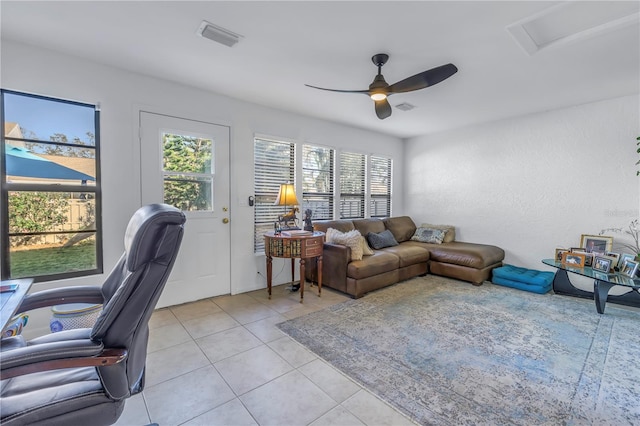 living area featuring light tile patterned floors, attic access, visible vents, and a ceiling fan