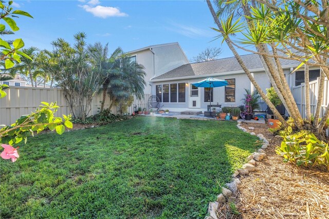 rear view of house featuring a fenced backyard, a lawn, and stucco siding