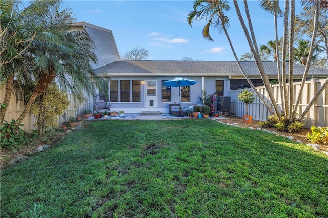 rear view of property with fence, a lawn, and stucco siding