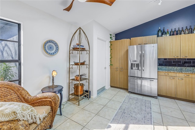 kitchen with plenty of natural light, vaulted ceiling, stainless steel refrigerator with ice dispenser, and light tile patterned floors