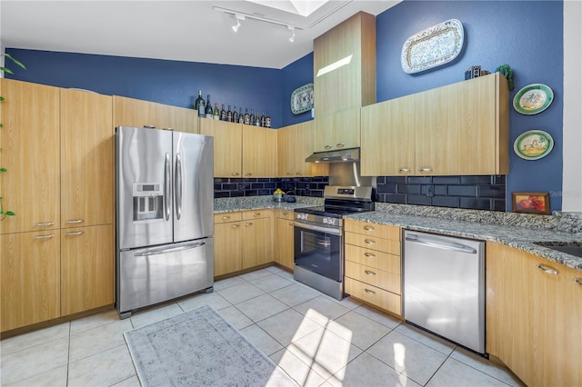 kitchen featuring appliances with stainless steel finishes, backsplash, under cabinet range hood, and light stone countertops