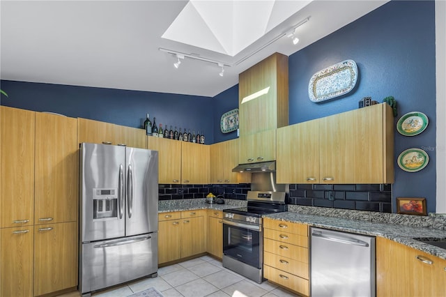 kitchen with light tile patterned floors, rail lighting, backsplash, appliances with stainless steel finishes, and under cabinet range hood