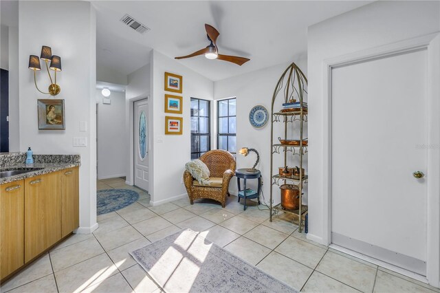 sitting room with light tile patterned floors, baseboards, visible vents, and a ceiling fan