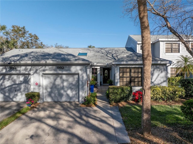 view of front facade featuring an attached garage, concrete driveway, and roof with shingles
