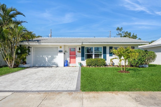 single story home featuring a front lawn, decorative driveway, and an attached garage